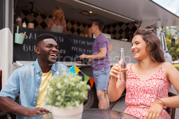 friends with drinks sitting at table at food truck Stock photo © dolgachov