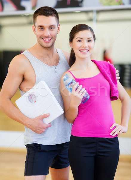 two smiling people with scale in the gym Stock photo © dolgachov