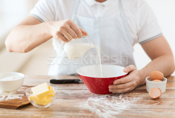 Közelkép férfi kéz áramló tej tál Stock fotó © dolgachov