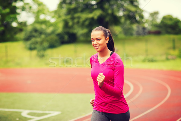 smiling young woman running on track outdoors Stock photo © dolgachov