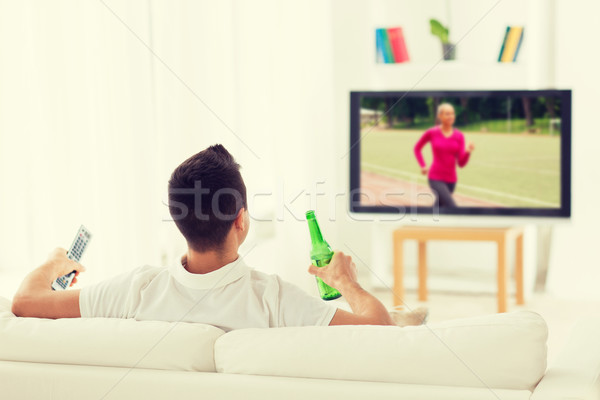 man watching sport on tv and drinking beer at home Stock photo © dolgachov