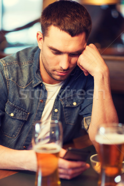 man with smartphone and beer texting at bar Stock photo © dolgachov