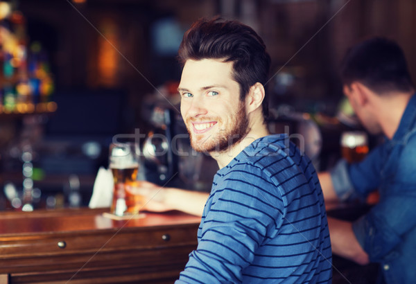 happy young man drinking beer at bar or pub Stock photo © dolgachov
