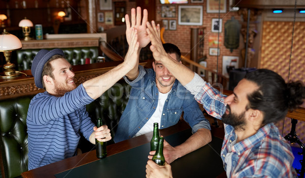 men with beer making high five at bar or pub Stock photo © dolgachov