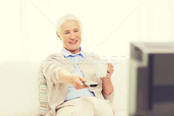 senior woman watching tv and drinking tea at home Stock photo © dolgachov