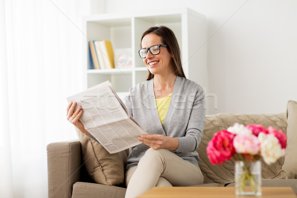 Stock photo: happy woman reading newspaper at home