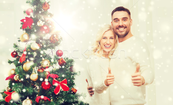 happy couple showing thumbs up with christmas tree Stock photo © dolgachov