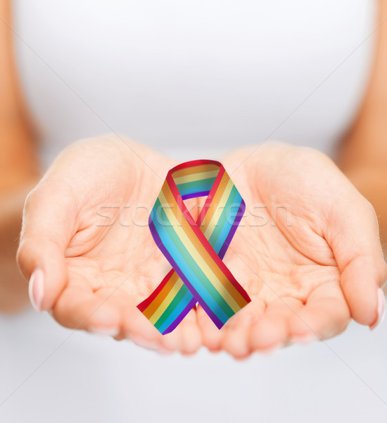 female hands holding gay pride awareness ribbon Stock photo © dolgachov