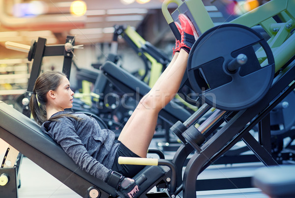 Stock photo: woman flexing muscles on leg press machine in gym