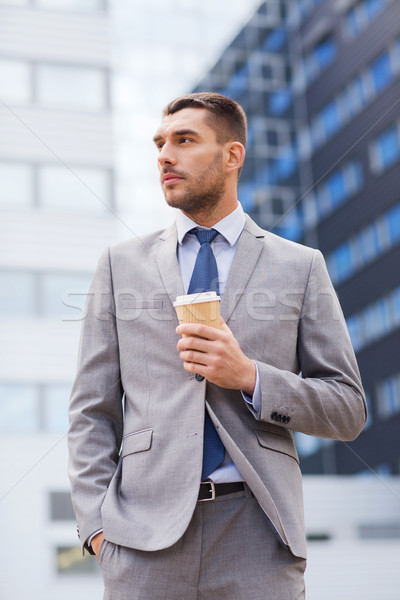 young serious businessman with paper cup outdoors Stock photo © dolgachov