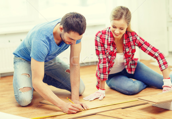 smiling couple measuring wood flooring Stock photo © dolgachov