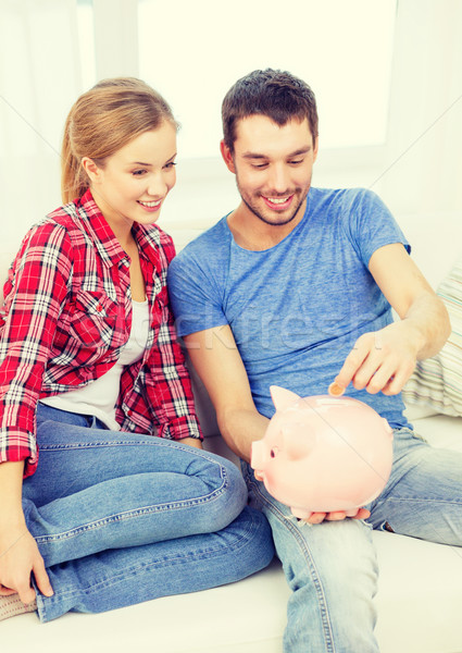 smiling couple with piggybank sitting on sofa Stock photo © dolgachov