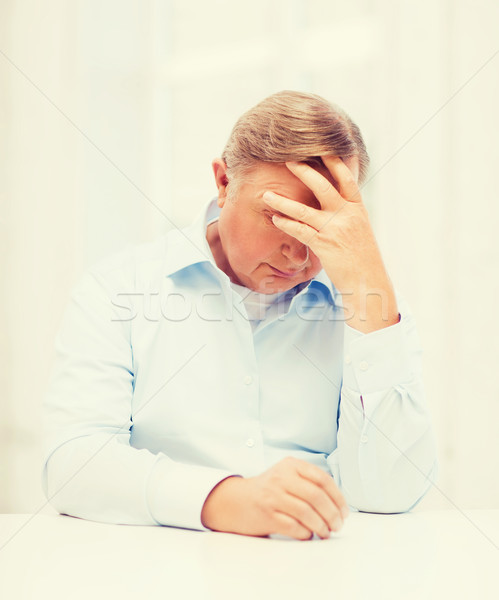 stressed old man holding head at home Stock photo © dolgachov