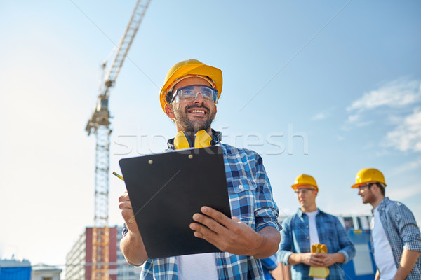 Stock photo: builder in hardhat with clipboard at construction