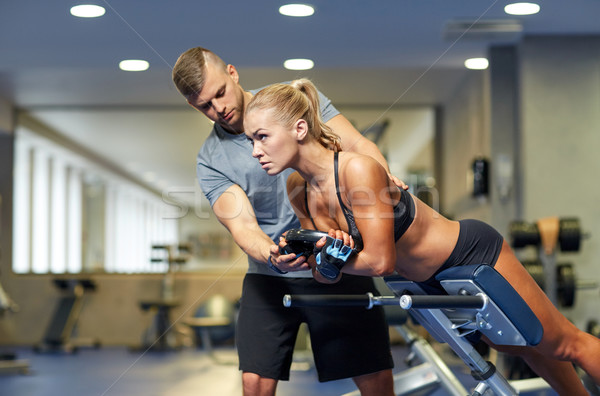woman with personal trainer flexing muscles in gym Stock photo © dolgachov