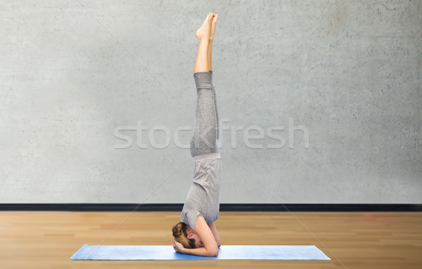 woman making yoga in headstand pose on mat Stock photo © dolgachov