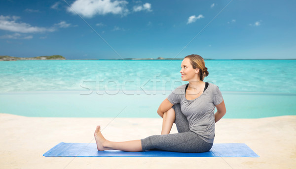 woman making yoga in twist pose on mat over beach  Stock photo © dolgachov