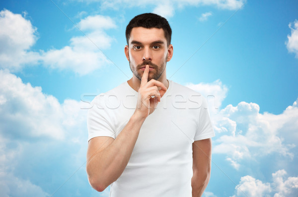 young man making hush sign over blue sky Stock photo © dolgachov