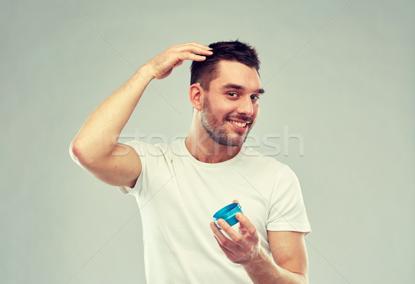 happy young man styling his hair with wax or gel Stock photo © dolgachov