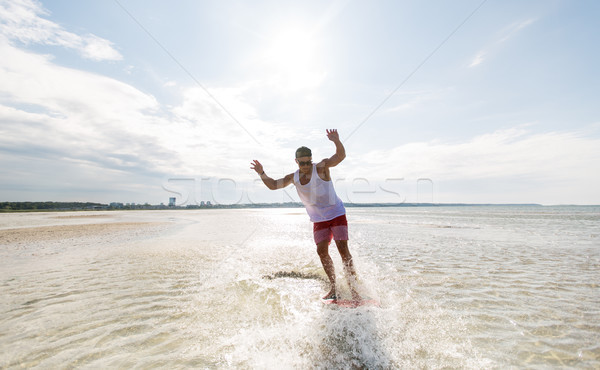 young man riding on skimboard on summer beach Stock photo © dolgachov