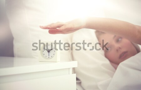 close up of woman with alarm clock in bed at home Stock photo © dolgachov