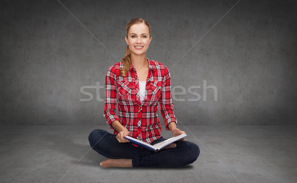 smiling young woman sittin on floor with book Stock photo © dolgachov