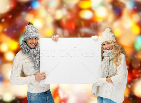 smiling couple in winter clothes with blank board Stock photo © dolgachov