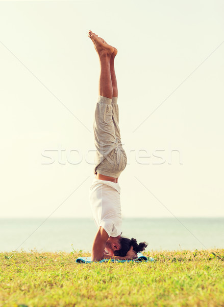 man making yoga exercises outdoors Stock photo © dolgachov