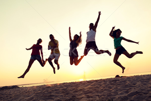 smiling friends dancing and jumping on beach Stock photo © dolgachov