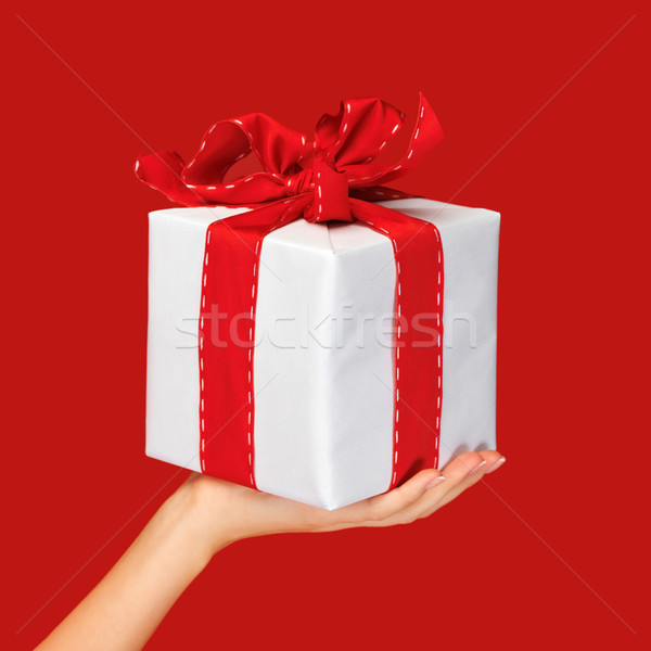 close up hand holding christmas gift box over red Stock photo © dolgachov