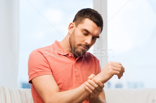 unhappy man suffering from pain in hand at home Stock photo © dolgachov