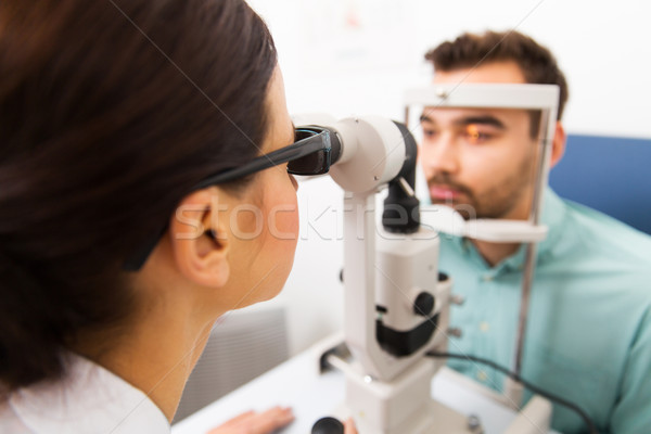 optician with slit lamp and patient at eye clinic Stock photo © dolgachov