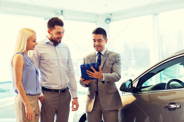 happy couple with car dealer in auto show or salon Stock photo © dolgachov