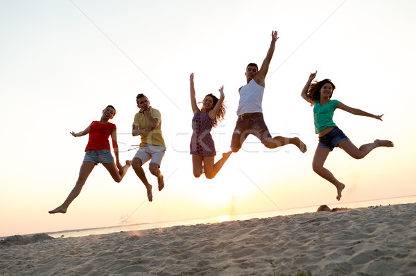 smiling friends dancing and jumping on beach Stock photo © dolgachov