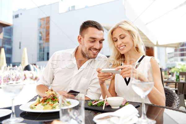 happy couple with smatphone at restaurant terrace Stock photo © dolgachov