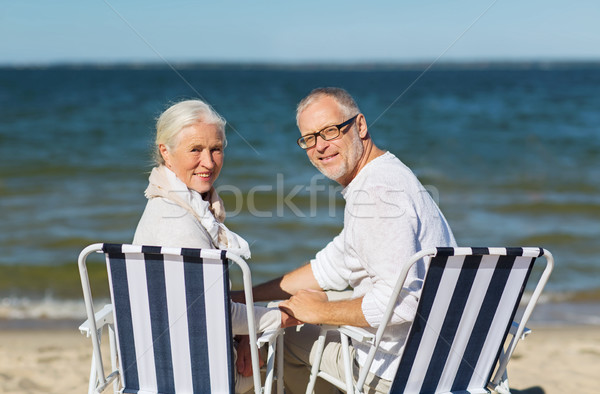 senior couple sitting on chairs at summer beach Stock photo © dolgachov