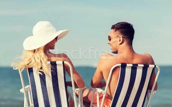 happy couple sunbathing in chairs on summer beach Stock photo © dolgachov