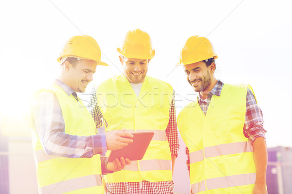 smiling builders in hardhats with tablet pc Stock photo © dolgachov