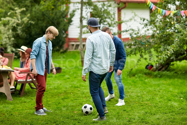 Szczęśliwy znajomych gry piłka nożna lata ogród Zdjęcia stock © dolgachov