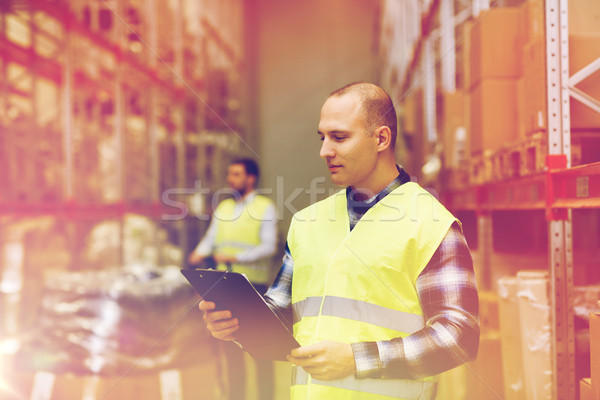 man with clipboard in safety vest at warehouse Stock photo © dolgachov