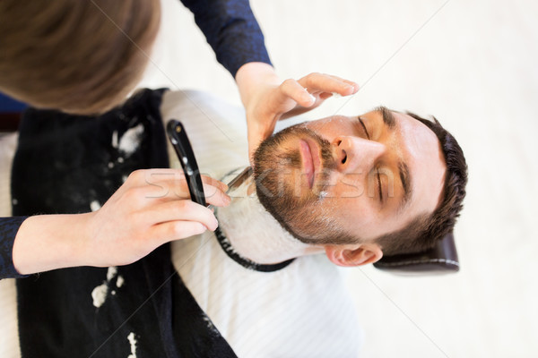 man and barber with straight razor shaving beard Stock photo © dolgachov