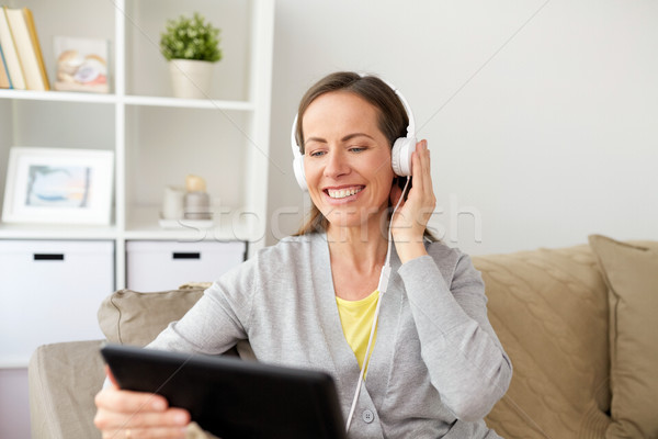happy woman with tablet pc and headphones at home Stock photo © dolgachov