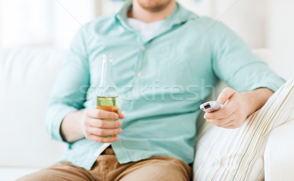 man with beer and remote control at home Stock photo © dolgachov