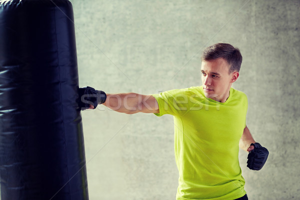 young man in gloves boxing with punching bag Stock photo © dolgachov