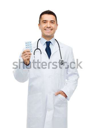smiling male doctor in white coat with tablets Stock photo © dolgachov