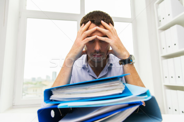Stock photo: sad businessman with stack of folders at office