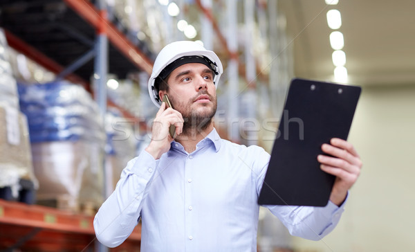 man with clipboard and smartphone at warehouse Stock photo © dolgachov