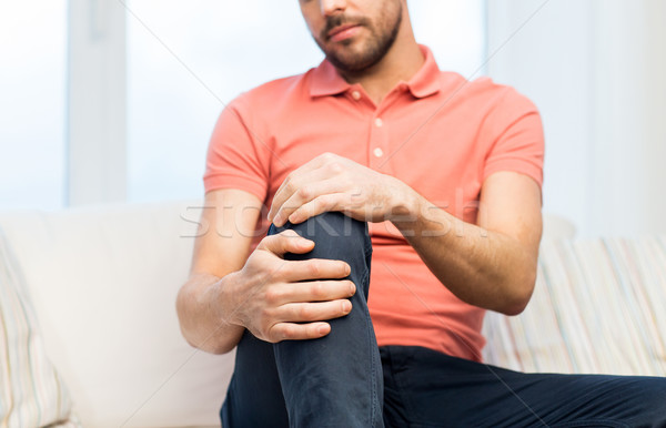close up of man suffering from pain in leg at home Stock photo © dolgachov