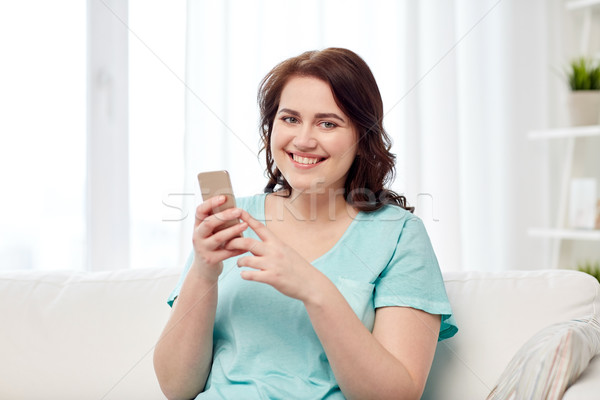 happy plus size woman with smartphone at home Stock photo © dolgachov