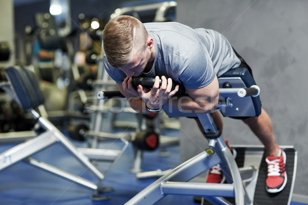young man flexing back muscles on bench in gym Stock photo © dolgachov